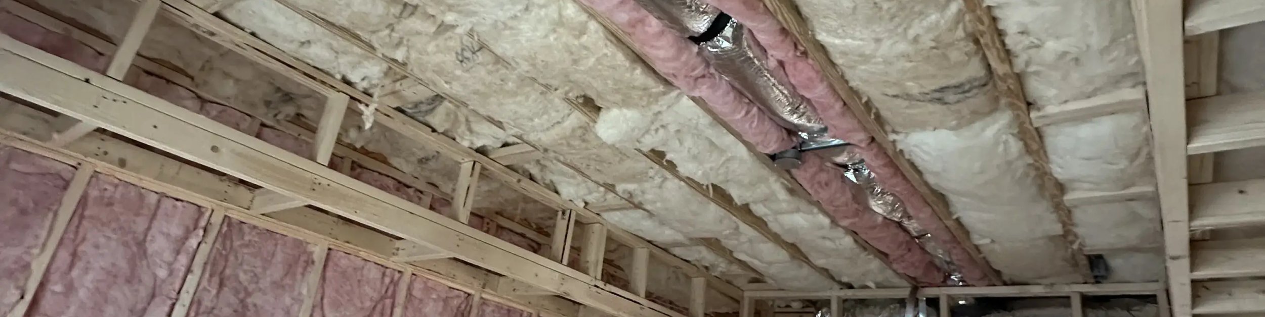 Fiberglass batt insulation installed around ductwork between framing