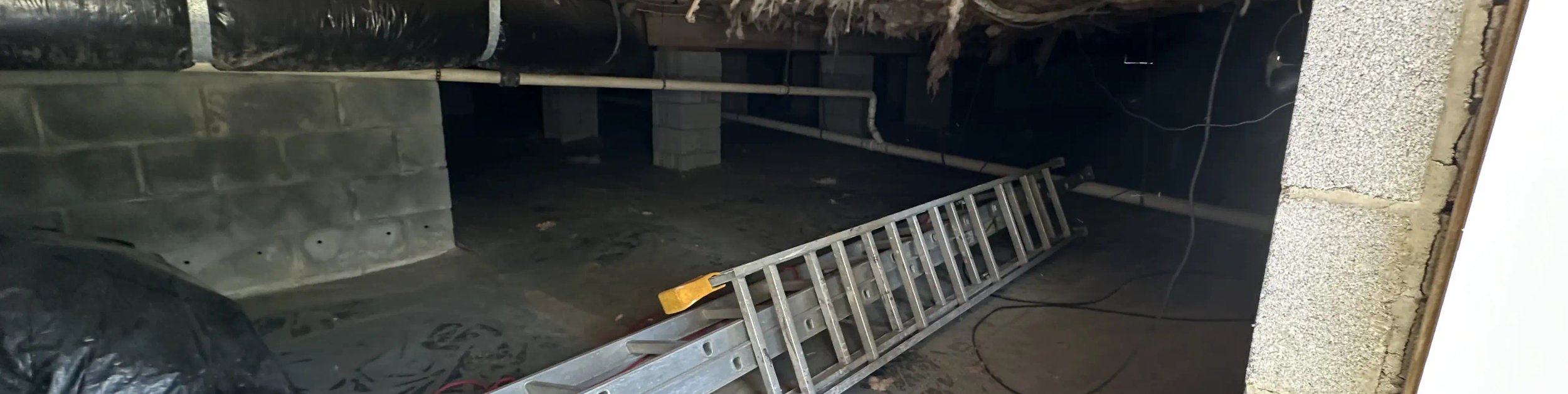 Durham crawl space before work, with drooping fiberglass insulation and a dark dirt floor