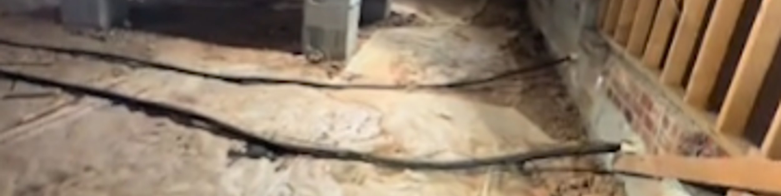 Crawl space with a bare dirt floor and exposed piers before encapsulation