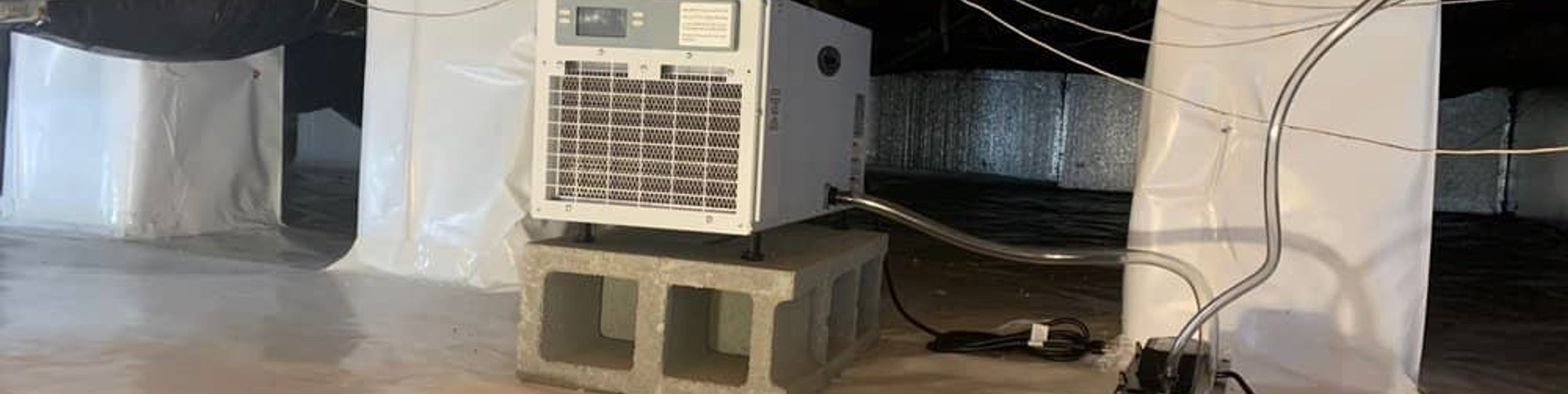 Crawl space dehumidifier on a cinder block above the vapor barrier